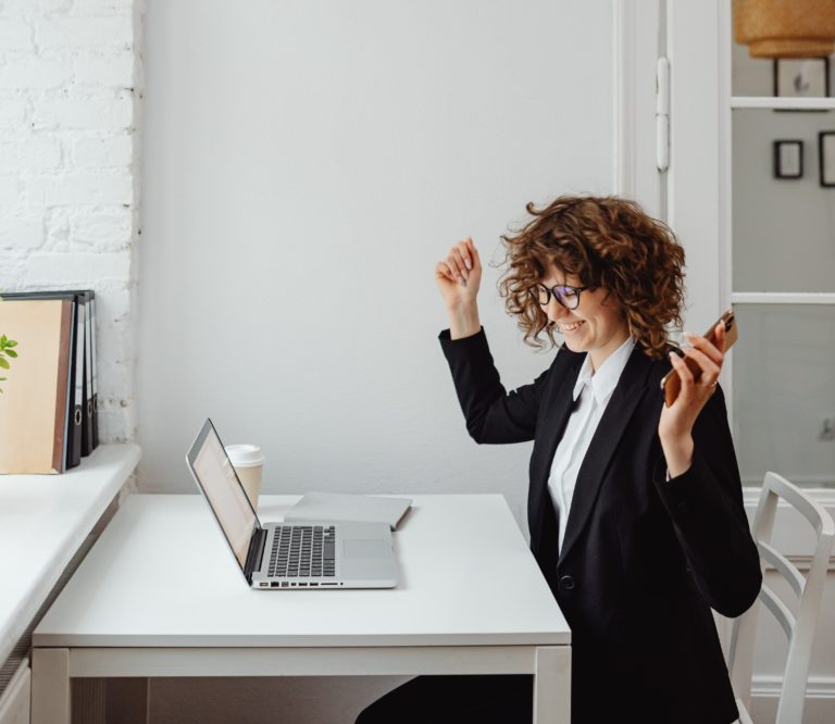 an entrepreneur sits in her computer chair and is excited. Getting organized has attributed to success!