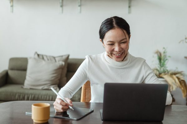 Woman drawing on her Wacom Tablet while also on the laptop